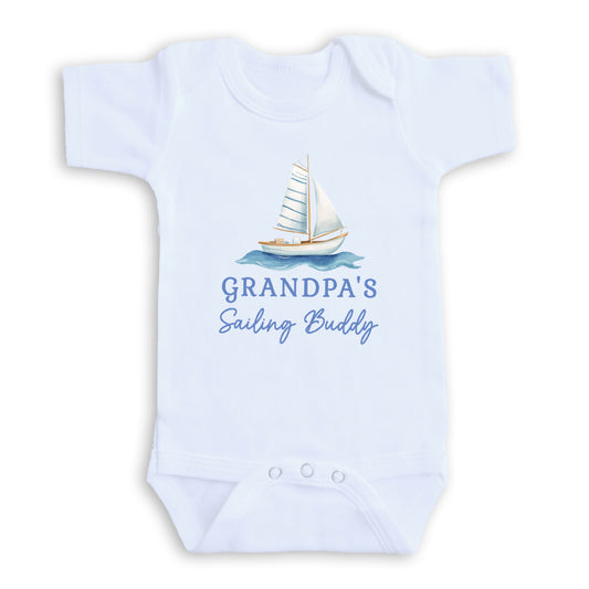 A white baby onesie with a sailboat graphic and the text "Grandpa's Sailing Buddy" printed on it.