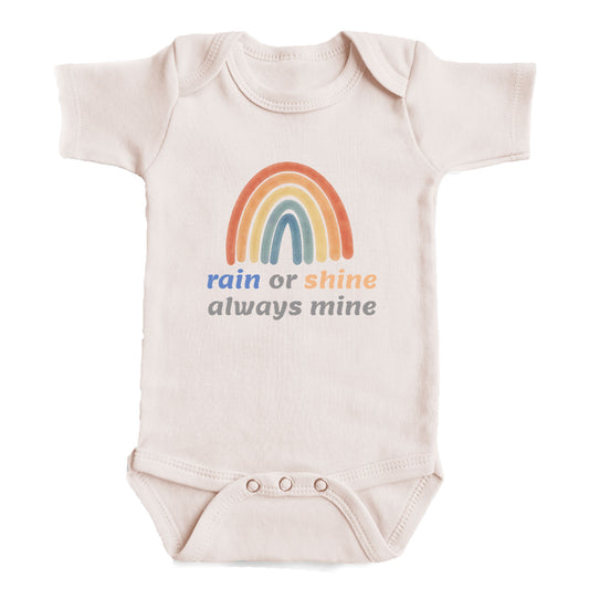 A baby onesie with a rainbow graphic and the text "rain or shine always mine" printed on it.