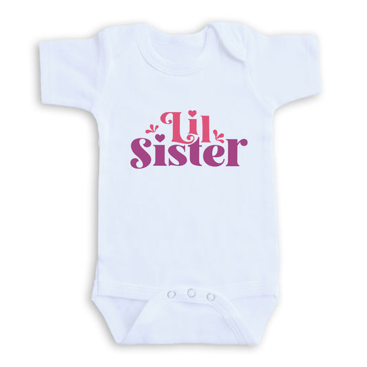 A white baby onesie with the text "Little Sister" printed on it in pink and purple lettering.