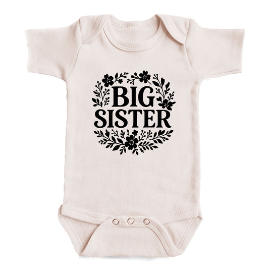 A baby onesie with the text "BIG SISTER" printed on it.