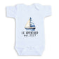 A white baby onesie with a sailboat graphic and the text "LIL' ADVENTURER est. 2027" printed on it.