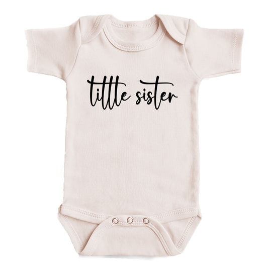 A baby onesie with the text "tittle sister" printed on it.
