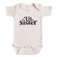 A baby onesie with the text "Lil Sister" printed on it.