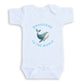 A white baby onesie with a graphic of a whale and the text "Whalecome to the World" printed on it.