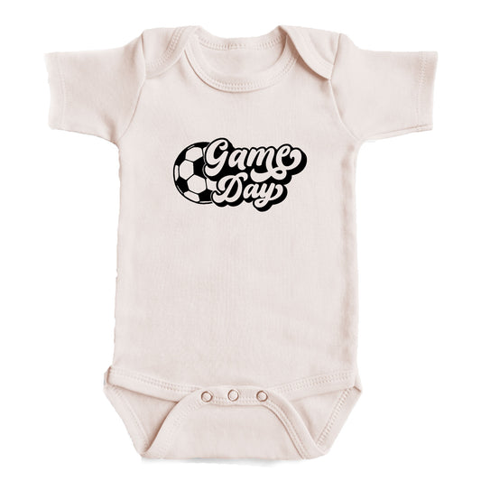 A baby onesie with the text "Game Day" printed on it.
