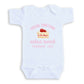 A white baby onesie with a pink graphic and text on it.