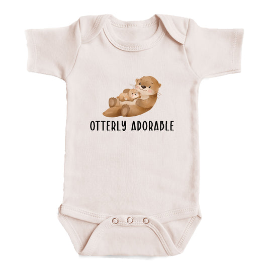 A baby onesie with an image of an otter and the text "OTTERLY ADORABLE" printed on it.