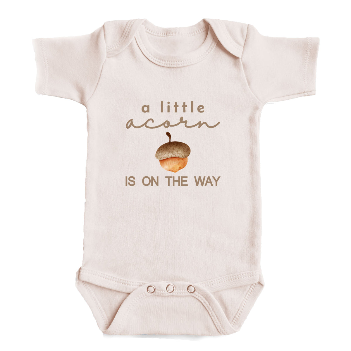 A baby onesie with the text "a little acorn is on the way" printed on it.