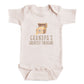 A baby onesie with a graphic of a chest containing gold coins and the text "GRANDPA'S GREATEST TREASURE" printed on it.