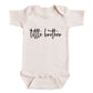 A baby onesie with the text "tittle brother" printed on it.