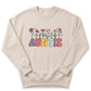A beige sweatshirt with the word "Auntie" printed on it in a colorful, flower-like font.