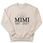 A beige sweatshirt with the text "Mimi EST. 2027" printed on it.