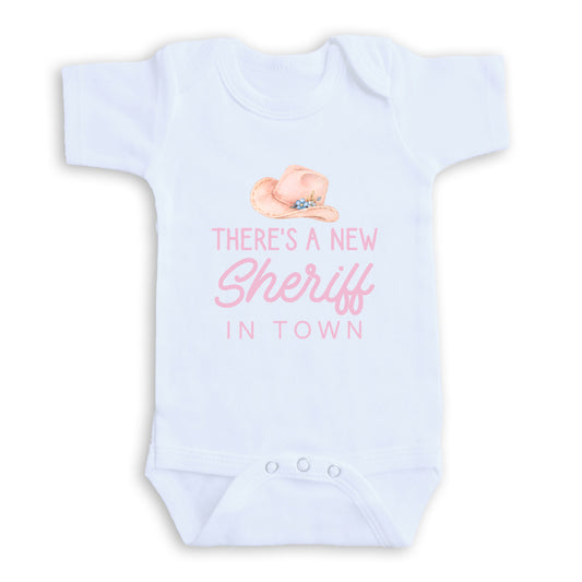 The image is a white baby onesie with a printed message that reads "There's a new Sheriff in town".