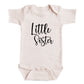 A baby onesie with the text "Little Sister" printed on it.