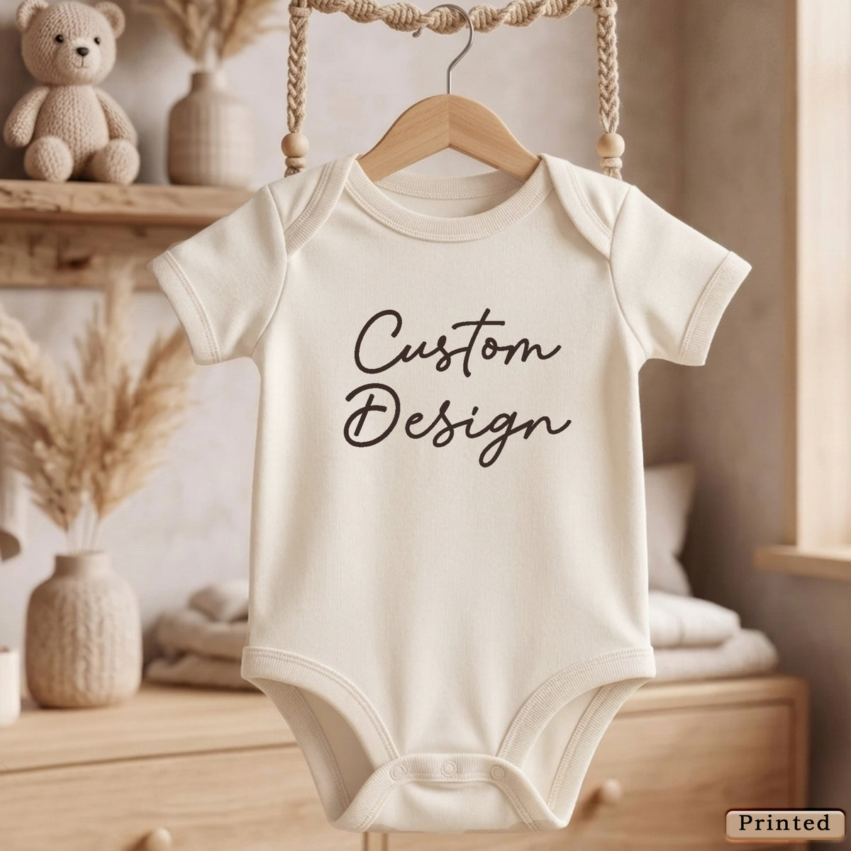 A white baby onesie with the text "Custom Design" printed on it, hanging on a wooden hanger.