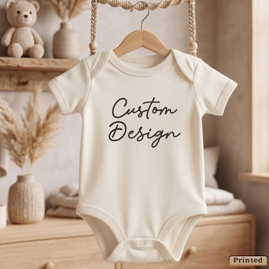 A white baby onesie with the text "Custom Design" printed on it, hanging on a wooden hanger.