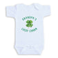A white baby onesie with a green clover design and the text "GRANDPA'S LUCKY CHARM" printed on it.