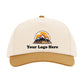 A white baseball cap with a graphic design featuring mountains and a sunset.