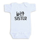 A white baby onesie with the text "big sister" printed on it.