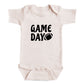 A baby onesie with the text "GAME DAY" printed on it.