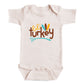 A baby onesie with the text "Lil' turkey" printed on it.