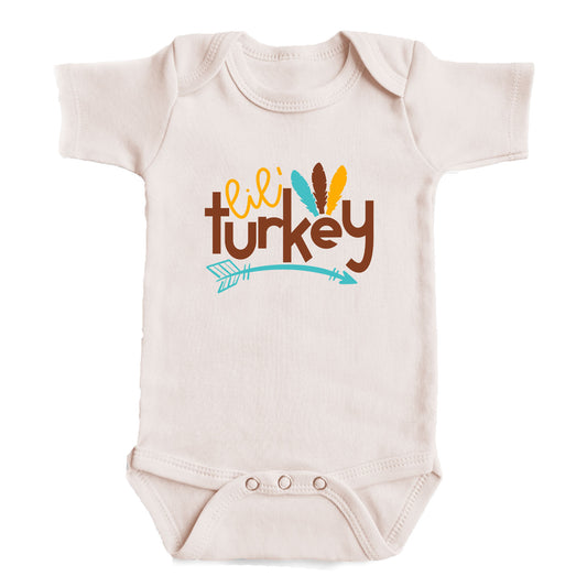 A baby onesie with the text "Lil' turkey" printed on it.