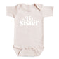 A baby onesie with the text "Little Sister" printed on it.