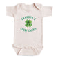 A baby onesie with the text "GRANDPA'S LUCKY CHARM" printed on it, along with a cloverleaf graphic.
