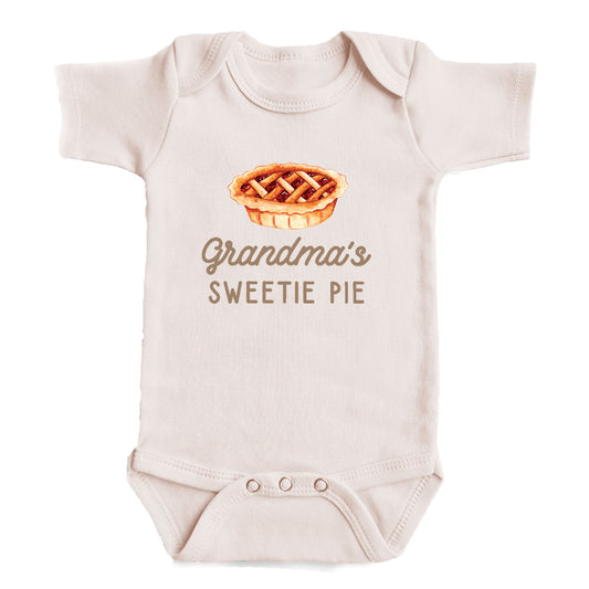 A baby onesie with a printed image of a pie and the text "Grandma's SWEETIE PIE" printed on it.