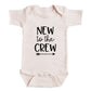 A baby onesie with the text "NEW to the CREW" printed on it.
