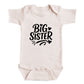 A baby onesie with the text "BIG SISTER" printed on it.