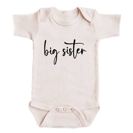A baby onesie with the text "big sister" printed on it.