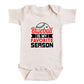 A white baby onesie with a printed text that says "Baseball is my favorite season".