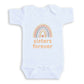 A white baby onesie with a rainbow graphic and the text "sisters forever" printed on it.