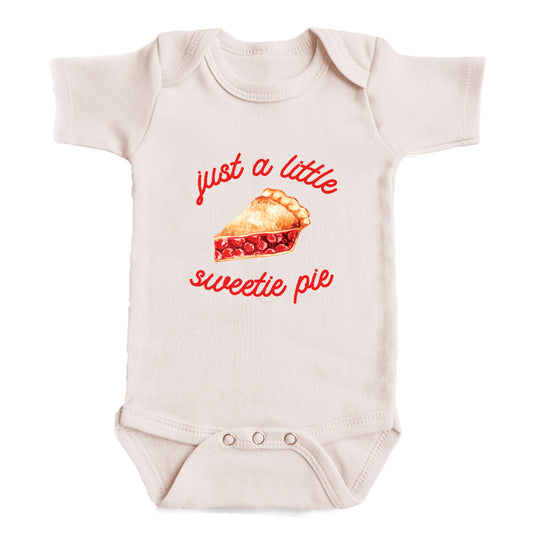 A baby onesie with a printed design of a pie and the text "Just a little sweetie pie" on it.