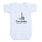 A white baby onesie with a sailboat graphic and text that reads "A new adventure JANUARY 2027".