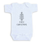 A white baby onesie with a black Christmas tree graphic and the text "FIRST CHRISTMAS" printed on it.