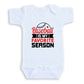 A white baby onesie with a printed text that says "Baseball is my favorite season".