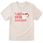 A beige t-shirt with a red graphic design that says "HOT COCOA SEASON" and features a Santa Claus or Christmas character.