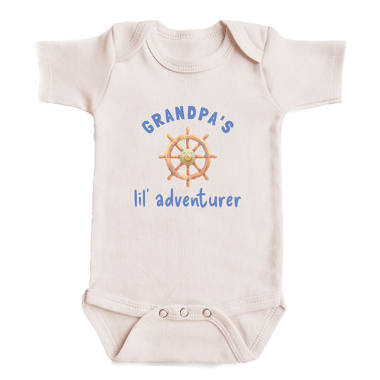 A baby onesie with the text "GRANDPA'S lil' adventurer" printed on it, along with a graphic of a steering wheel.