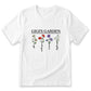 A white t-shirt with a graphic design featuring four different flowers, each with a unique color and style, along with the text "GIGI'S GARDEN".