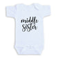 A white baby onesie with the text "middle sister" printed on it.