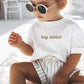 A child wearing a white shirt with gold font reading "big sister"