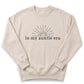 A beige sweatshirt with a graphic design and text printed on it.