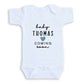 A white baby onesie with the text "baby Thomas coming soon" printed on it.