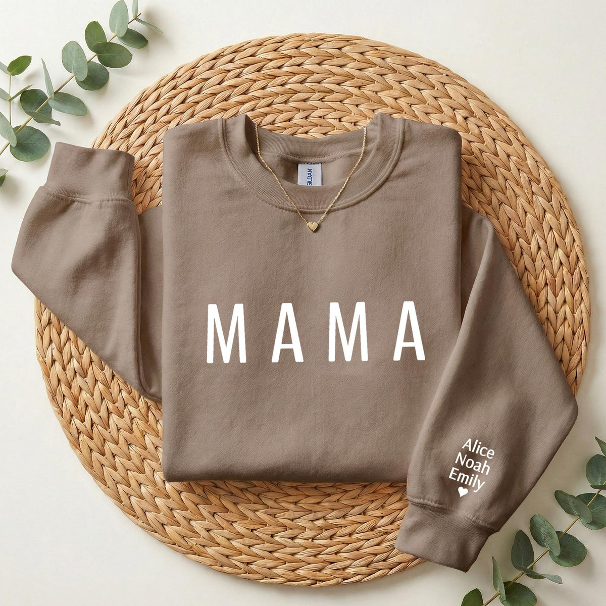 A brown sweatshirt with the word "MAMA" printed on it, placed on a woven placemat.