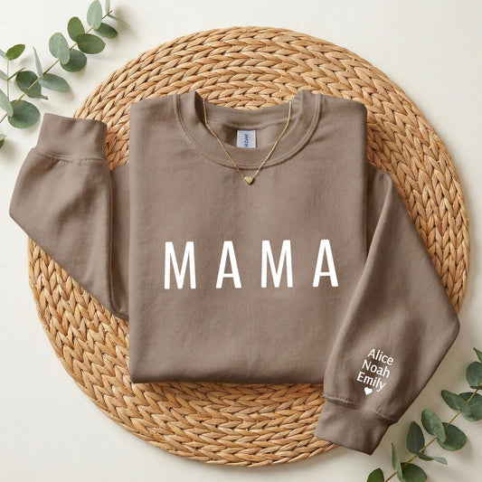 A brown sweatshirt with the word "MAMA" printed on it, placed on a woven placemat.