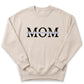 A beige sweatshirt with the word "MOM" printed on it in large black letters.