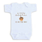 A white baby onesie with the text "a little acorn is on the way" printed on it.