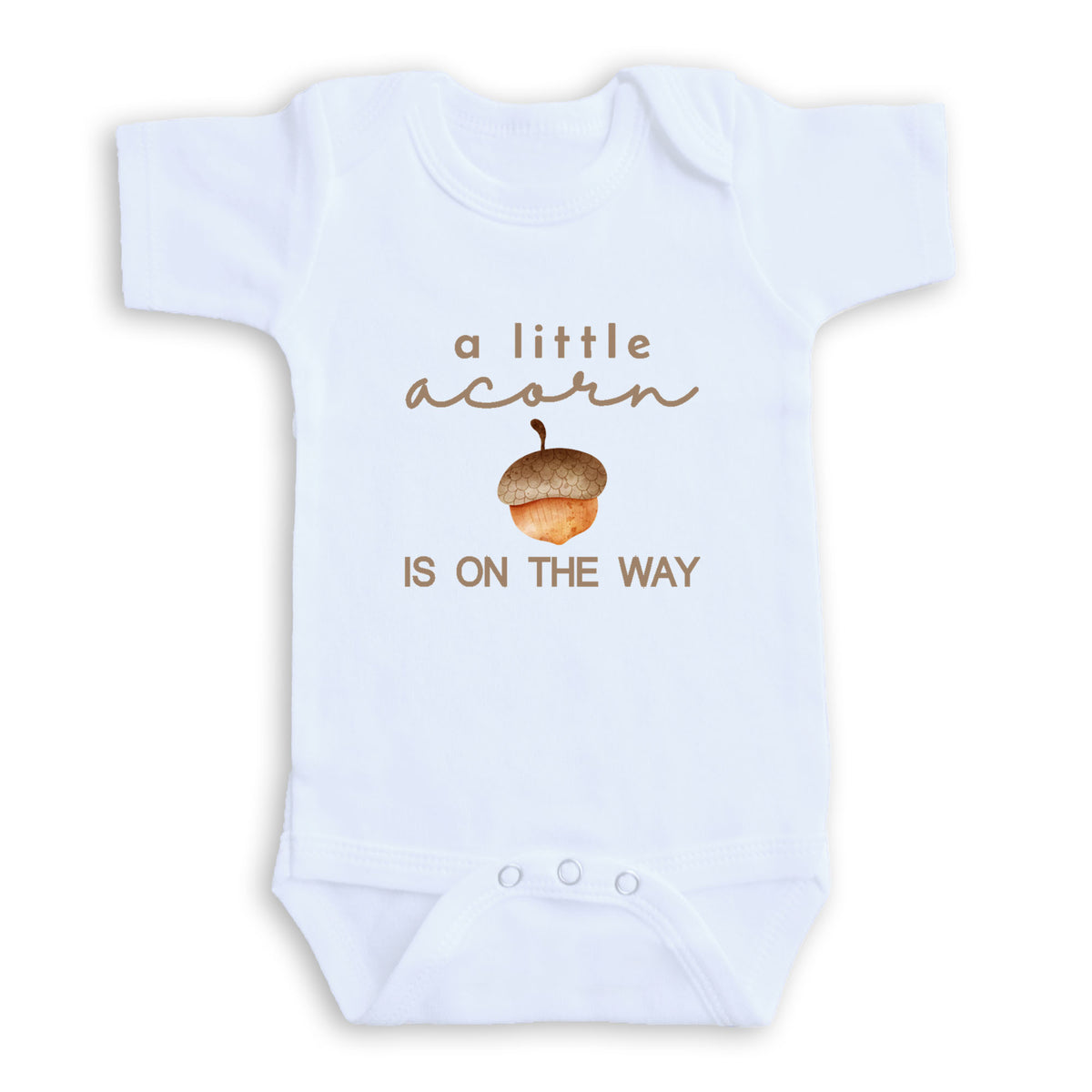 A white baby onesie with the text "a little acorn is on the way" printed on it.